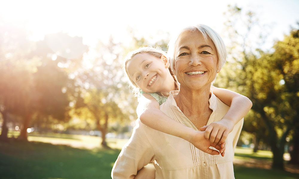 A woman and a young child smiling with the sun behind them